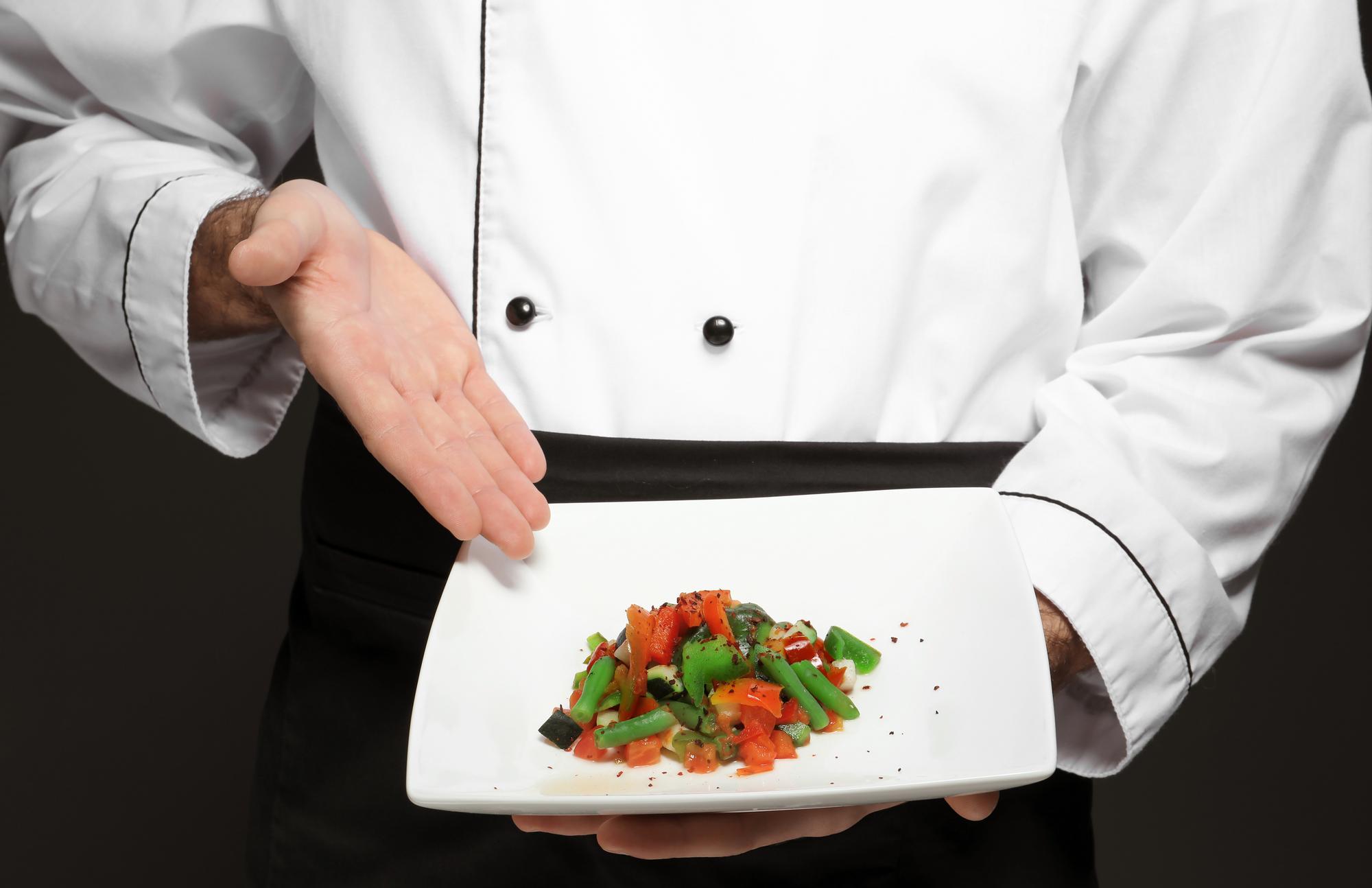 Chef demonstrating plated dish in elegant kitchen